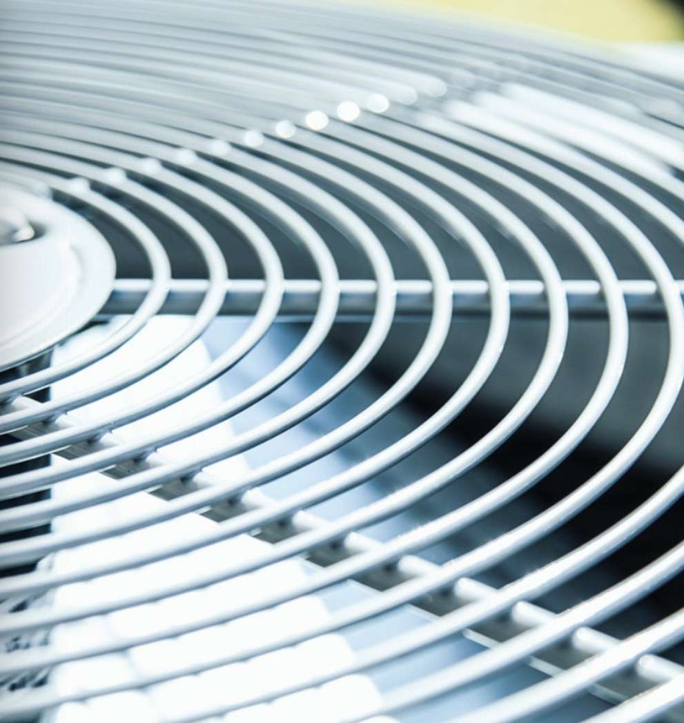 Close-up view of metal grilles on a circular Squamish HVAC air conditioning unit, showing curved silver bars and the fan beneath.